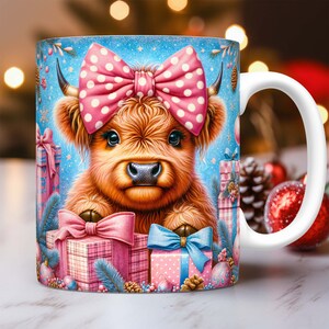 May include: A white ceramic mug with a handle features a festive illustration of a Highland cow wearing a pink polka dot bow. The cow is surrounded by wrapped presents and Christmas ornaments on a blue background.