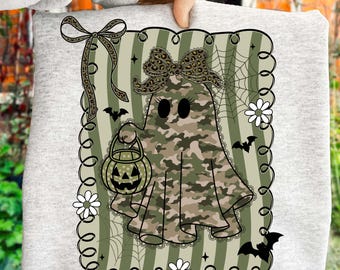 May include: A light gray sweatshirt featuring a Halloween-themed ghost design. The ghost is in camouflage print, holding a jack-o'-lantern bucket. The design includes bats, spiderwebs, and daisies. A bow and ribbon are at the top left.