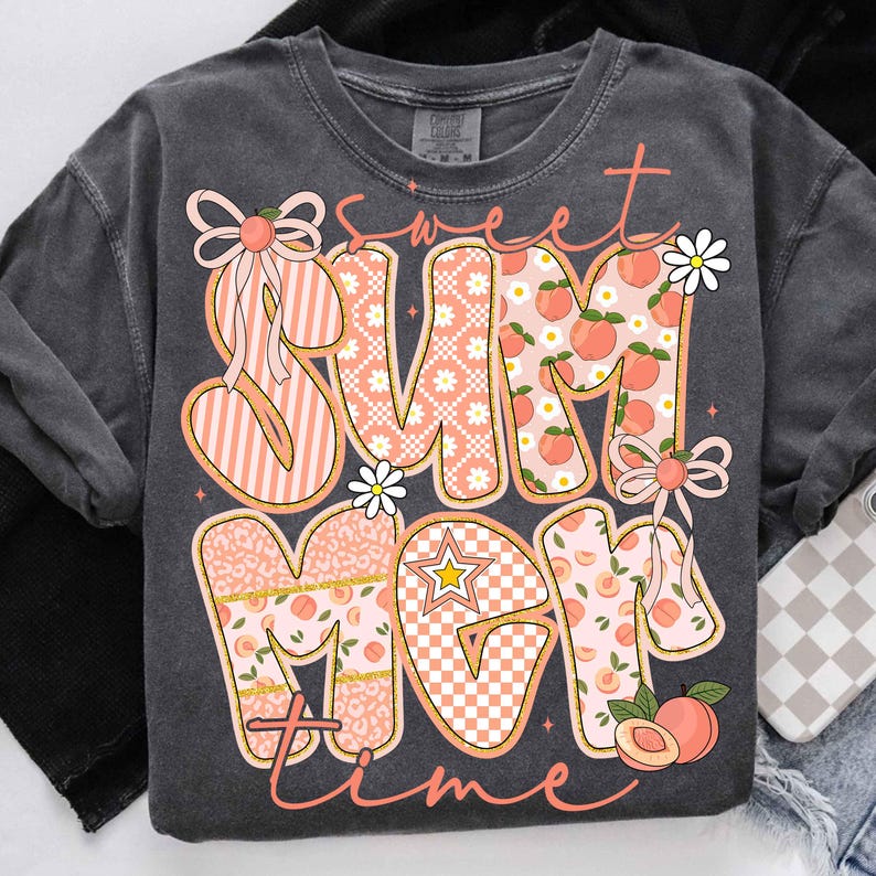 以下が含まれることがあります： 「Sweet Sum Mom Time」の文字がピーチと白のデザインで描かれた濃いグレーのTシャツ。文字はストライプ、桃、花柄で装飾されています。デザインにはリボン、デイジー、星が含まれています。