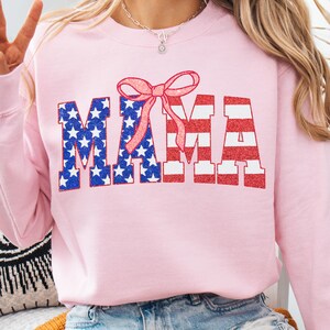 May include: Pink sweatshirt with a glittery red, white, and blue "MAMA" design with a pink bow on top.