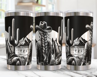May include: Three stainless steel tumblers with a black and white design of a woman riding a horse in a desert landscape with cacti. The design is a silhouette with a western theme.