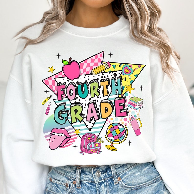 K&ouml;nnte beinhalten: Wei&szlig;er Pullover mit einem bunten Grafikdesign mit den Worten "FOURTH GRADE" im Retro-Stil. Das Design enth&auml;lt eine Vielzahl von schulthemenbezogenen Symbolen, wie einen Apfel, einen Bleistift, einen Rucksack und einen Globus.