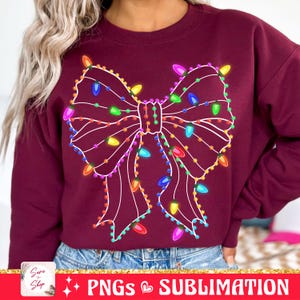 May include: A maroon sweatshirt with a white outline of a bow made of Christmas lights. The lights are multi-colored and glow.