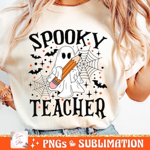 May include: A white t-shirt with a black and white illustration of a ghost holding a pencil. The text "Spooky Teacher" is printed in black below the ghost. The design is surrounded by orange and black bats, stars, and spiderwebs.