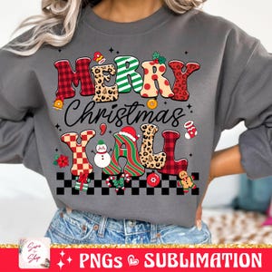 Pu&ograve; includere: Una felpa grigia con un design natalizio festoso. Il testo "Merry Christmas Y'all" &egrave; scritto in lettere colorate e con motivi, con varie icone natalizie.