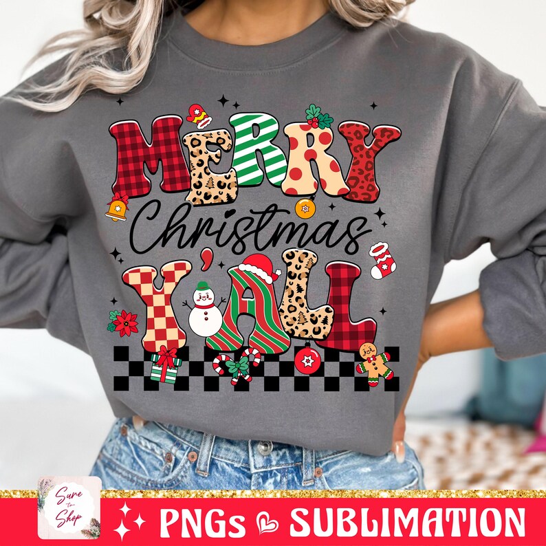 Pu&ograve; includere: Una felpa grigia con un design natalizio festoso. Il testo "Merry Christmas Y'all" &egrave; scritto in lettere colorate e con motivi, con varie icone natalizie.
