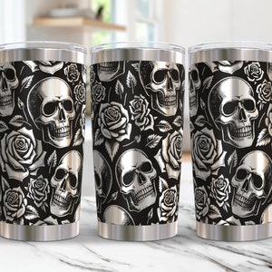 May include: Three stainless steel travel mugs with a black background and a repeating pattern of white skulls and roses. The mugs have a silver rim and base, and a clear lid.