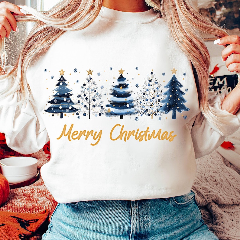 May include: White sweatshirt with a blue and gold Christmas tree design and the text "Merry Christmas".