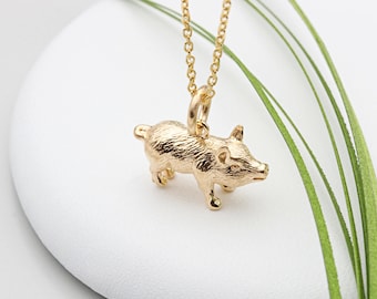 May include: A gold necklace with a small, detailed pig pendant. The pig is standing on all four legs and has a textured surface.