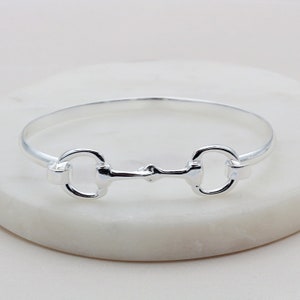 Puede incluir: Un brazalete de plata con un diseño de bocado. El brazalete es simple y elegante.