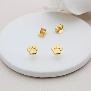 May include: A pair of gold-toned paw print stud earrings. The earrings are small and delicate, and they would make a great gift for any dog lover.