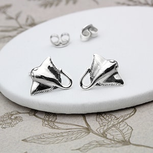 May include: A pair of silver earrings shaped like stingrays. The earrings are small and delicate, and they would make a great gift for anyone who loves the ocean.