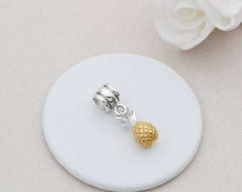 May include: A silver charm with a gold pineapple pendant. The charm is designed to fit on a bracelet or necklace.