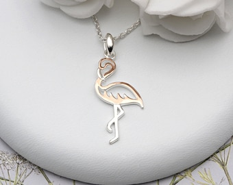 May include: A silver necklace with a rose gold flamingo pendant. The flamingo is cut out in a delicate design.