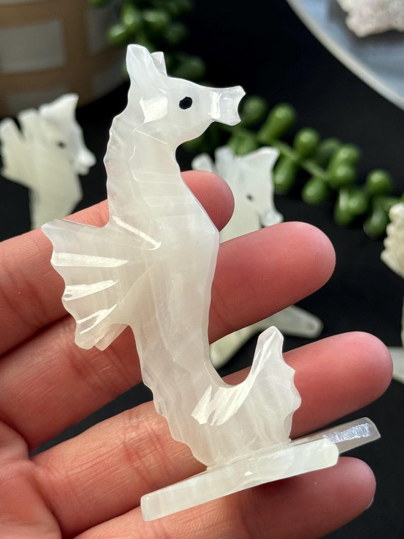 Puede incluir: Figurita de caballito de mar tallada en cristal de selenita blanco. La figurita est&aacute; de pie sobre una peque&ntilde;a base y tiene un dise&ntilde;o detallado.