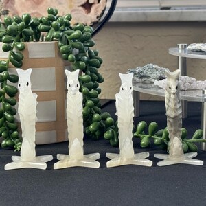 Puede incluir: Cuatro esculturas talladas en blanco de una criatura m&iacute;tica con una base en forma de estrella. Las esculturas est&aacute;n hechas de un material transl&uacute;cido y tienen un dise&ntilde;o delicado e intrincado.