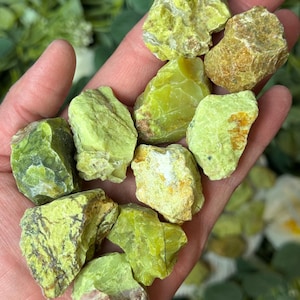 May include: A collection of green and yellow opal rough stones. The stones are various sizes and shapes, with some showing a hint of brown.