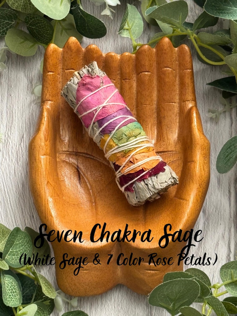 May include: A wooden hand-shaped dish holding a sage smudge stick wrapped in white string, decorated with seven layers of colored rose petals. The text Seven Chakra Sage (White Sage & 7 Color Rose Petals) is printed over the image.