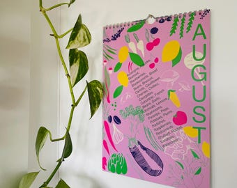 May include: A pink calendar with the word "AUGUST" in large white letters. The calendar lists a variety of fruits and vegetables that are in season during the month of August.