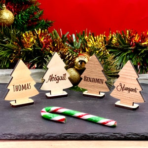 Configurações de lugar de árvore de Natal personalizadas, nomes gravados em madeira no suporte. Cartões de assento personalizados rústicos, ideia de decoração de mesa festiva