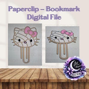 May include: A digital file featuring a paperclip and bookmark design. The design is a stylized cat face with a pink bow, black eyes, and a pink nose. The text "Paperclip - Bookmark Digital File" is at the top.