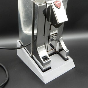 May include: A silver and chrome coffee maker with a red and white logo that says "Euradio". The coffee maker has a white plastic top with a black ribbed ring.