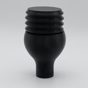 May include: Black rubber bottle stopper with a ribbed top and a round base. The stopper has the word "Paraly" printed on the bottom.