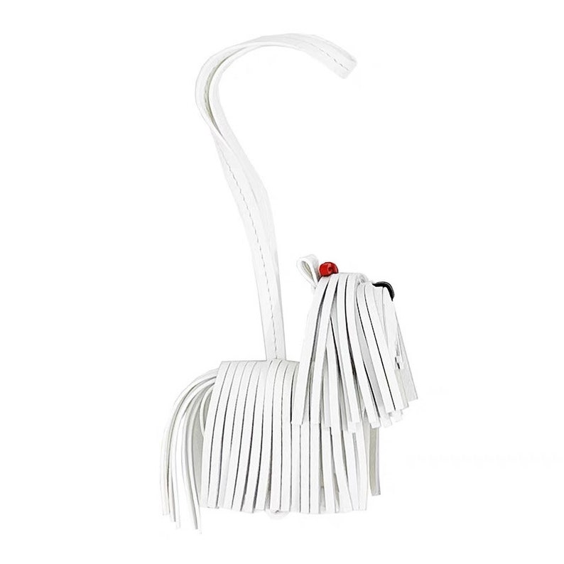 May include: White leather dog keychain with a long, flowing tail and a red bead for a nose.