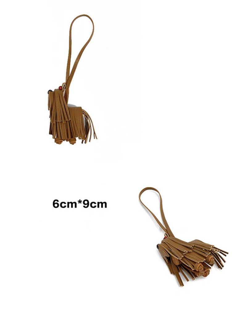 May include: A brown leather tassel keychain shaped like a dog with a 6cm by 9cm measurement. The keychain has a long brown strap.