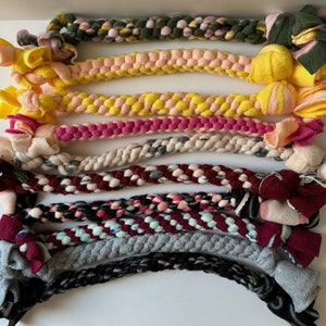 May include: Eight colorful braided dog toys with knotted ends. The toys are made of soft fabric and are designed for chewing and playing.