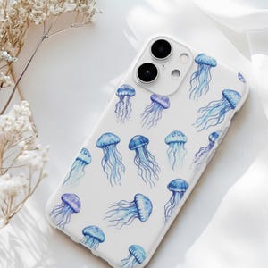 Puede incluir: Funda blanca para iPhone con un patrón de medusas azules y moradas en acuarela. La funda tiene un acabado brillante y un recorte para la cámara. El diseño incluye medusas de varios tamaños y orientaciones, creando un tema acuático.