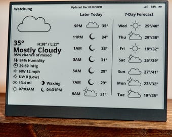 May include: A digital weather station displays current conditions: 35 degrees, mostly cloudy, 84% humidity, and a 7-day forecast. The screen shows the time, temperature, and weather icons. The device is on a wooden shelf.