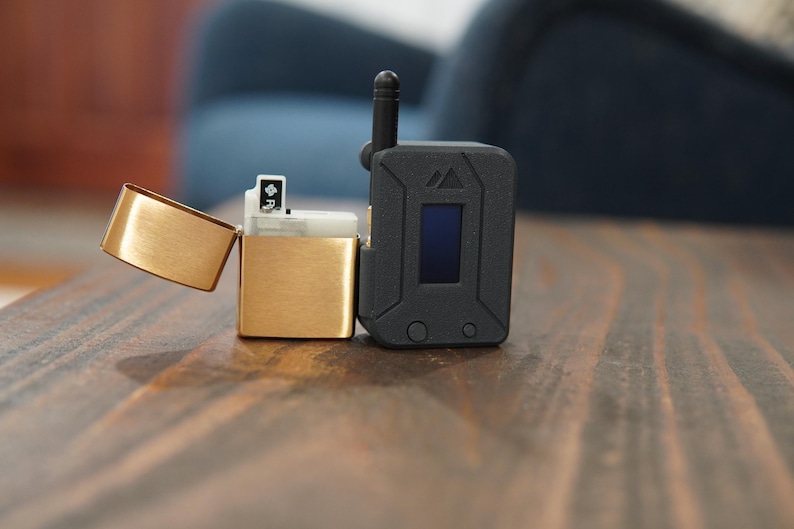 May include: A gold lighter with a black and silver device next to it. The device has a small screen and a button.