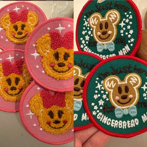 May include: Five pink and green embroidered iron-on patches featuring a gingerbread bear with a bow tie. The patches have white stars and the text "I'm just here for my gingerbread man".