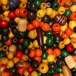 Może przedstawiać: Zbliżenie na kolekcję kolorowych drewnianych koralików o różnych kształtach. Koraliki są w odcieniach czerwieni, pomarańczy, żółci, zieleni i brązu. Niektóre koraliki są okrągłe, inne w kształcie beczułek lub podłużne. Idealne do rękodzieła lub tworzenia biżuterii.