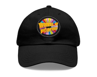 May include: Black baseball cap with a colorful Wheel of Fortune logo patch on the front. The patch features the iconic game show wheel with various dollar amounts and the words "Wheel of Fortune" in yellow.