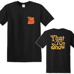 Puede incluir: Dos camisetas negras con el texto "That '70s Show" impreso en amarillo en la parte delantera y trasera.