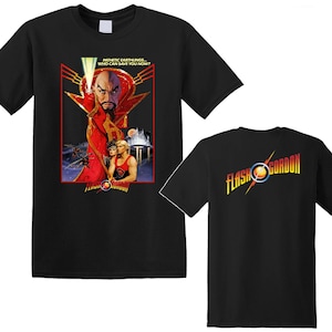 Può includere: Una t-shirt nera a maniche corte con una grafica di Flash Gordon. Il davanti mostra una scena con Ming lo Spietato, il testo "PATHETIC EARTHLINGS... WHO CAN SAVE YOU NOW?" e il logo "FLASH GORDON". Il retro presenta il logo "FLASH GORDON".