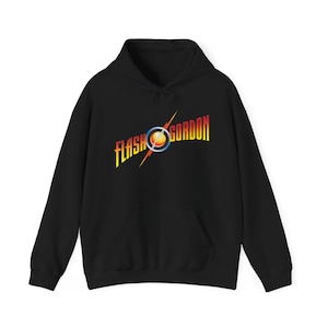 Może przedstawiać: Czarna bluza z kapturem z logo Flash Gordon w kolorze żółtym, pomarańczowym i czerwonym. Logo zawiera błyskawicę i okrągły wzór. Bluza ma przednią kieszeń i kaptur ze sznurkiem.