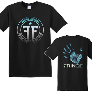 Puede incluir: Dos camisetas negras con un estampado gráfico en la parte delantera y trasera. La camiseta delantera tiene un círculo plateado con el texto "FRINGE DIVISION DEPARTMENT OF DEFENSE" y una estrella y las letras "FF" en su interior. La camiseta trasera tiene una huella de mano azul con el texto "FRINGE" debajo.