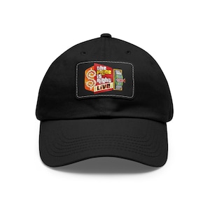 May include: Black baseball cap with a white and red embroidered patch that says "The Price is Right Live" with a dollar sign and a game show wheel.