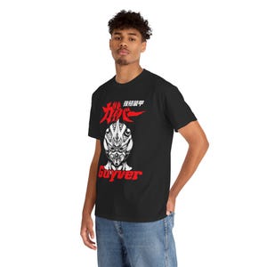 Puede incluir: Camiseta negra con un diseño gráfico rojo y blanco. El diseño incluye texto japonés y una ilustración estilizada de una cara de personaje. La palabra "Guyver" está impresa en rojo debajo.