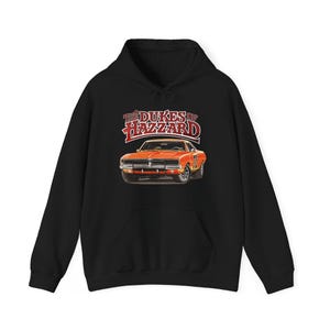 May include: Black hoodie with a graphic of an orange car and the text "The Dukes of Hazzard". The car has the number "01" on the door. The hoodie has a front pocket and a drawstring hood. The text is in red and white.