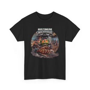 Puede incluir: Camiseta negra con un gráfico de la película "Maximum Overdrive". El diseño incluye un monstruo verde, un camión y el título de la película en letras plateadas. El monstruo está señalando al espectador.