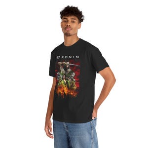 May include: Black t-shirt with a graphic from the film "47 Ronin." The design shows a warrior with a sword, figures in green and white, and flames. The text "47 RONIN" is printed above the graphic.