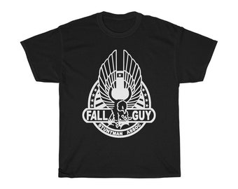 Pode incluir: Camiseta preta com um gráfico branco de uma águia estilizada com o texto "Fall Guy Stuntman Assoc."