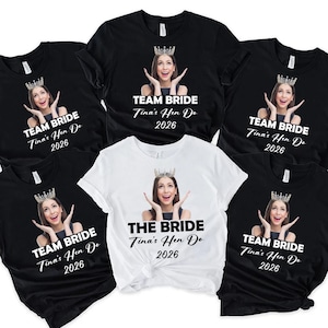 May include: A collection of five short-sleeved t-shirts, four black and one white, each featuring a photographic print of a person wearing a crown with hands near their face. The black shirts read TEAM BRIDE, while the white shirt reads THE BRIDE, all with Tina's Hen Do 2026.
