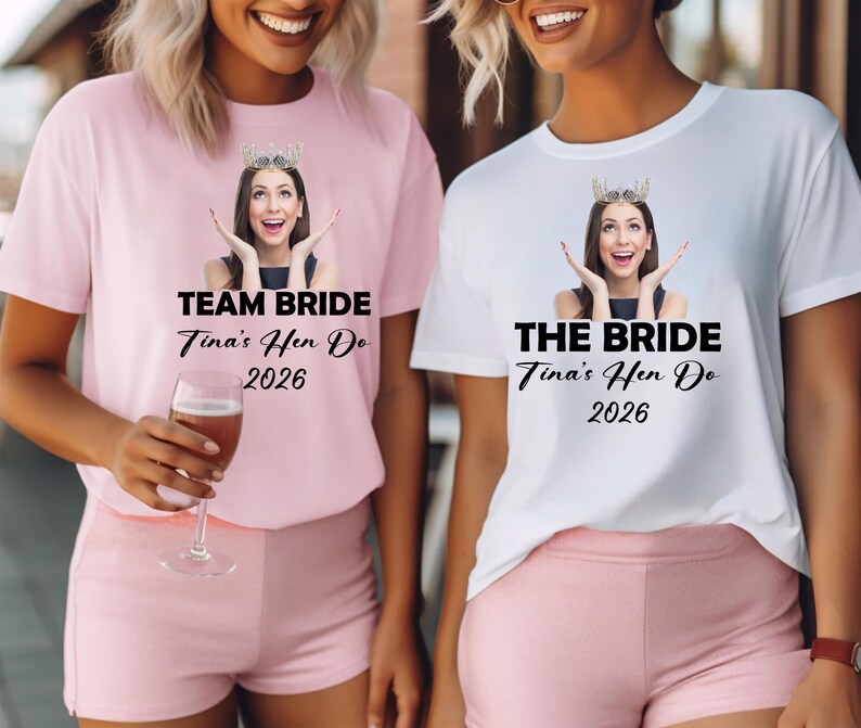 May include: A light pink t-shirt with the text TEAM BRIDE Tina's Hen Do 2026 and a white t-shirt with the text THE BRIDE Tina's Hen Do 2026. Both shirts feature a graphic of a person wearing a crown with hands raised near their face.