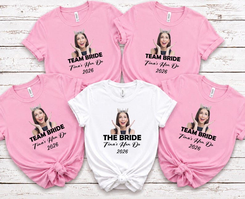 May include: Four light pink t-shirts and one white t-shirt, each featuring a printed photograph of a person wearing a crown, with the text TEAM BRIDE or THE BRIDE, followed by Tina's Hen Do 2026 in black lettering on the front of each garment.