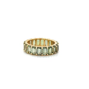 May include: A gold ring featuring a continuous band of rectangular, light green gemstones. The ring's band is a warm gold color, and the gemstones are evenly spaced around the circumference, creating a full eternity design.